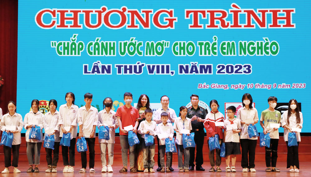 Description: Đồng chí Trần Văn Tuấn cùng đại diện Ban tổ chức và nhà tài trợ trao học bổng cho học sinh hoàn cảnh khó khăn.
